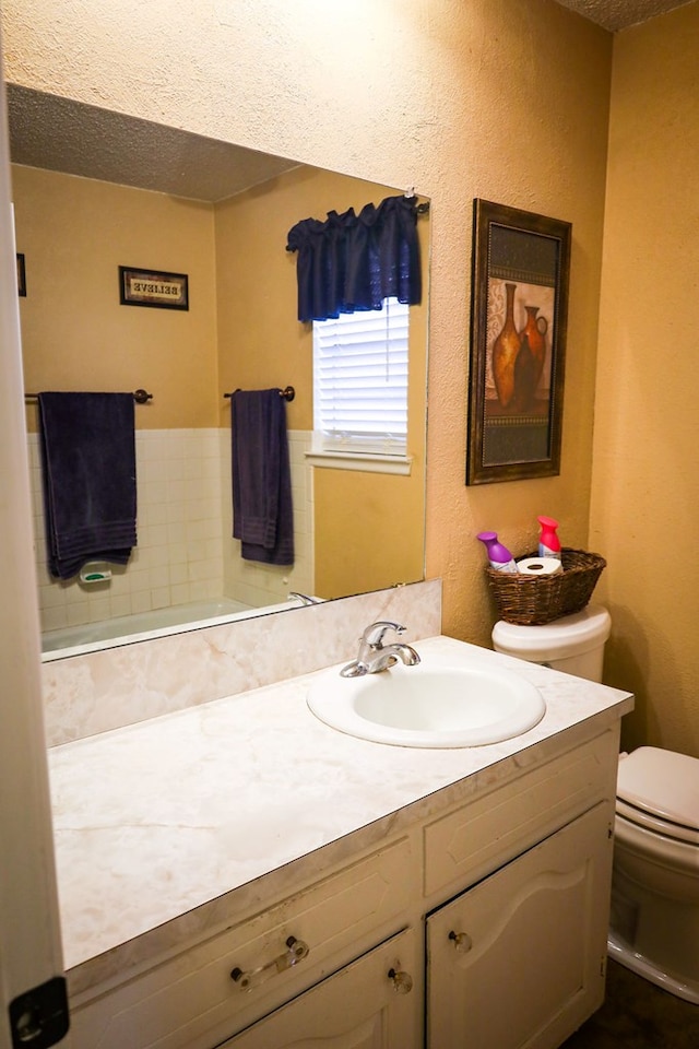 bathroom with vanity, a textured ceiling, and toilet