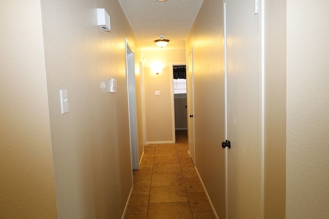 corridor with tile patterned flooring and a textured ceiling