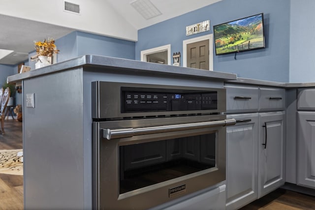 interior space featuring gray cabinetry, dark wood-type flooring, and stainless steel oven