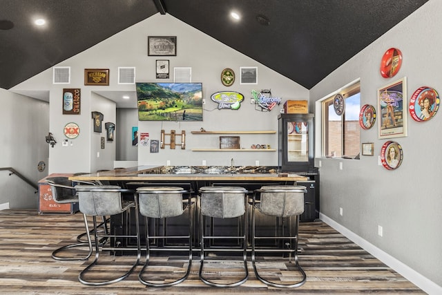 bar featuring wood-type flooring and lofted ceiling with beams