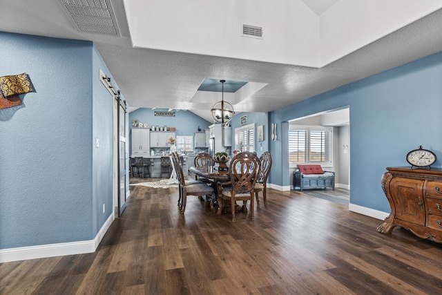 dining space with dark hardwood / wood-style flooring, lofted ceiling, a barn door, and a raised ceiling