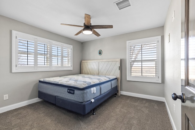 bedroom featuring ceiling fan, multiple windows, and dark colored carpet