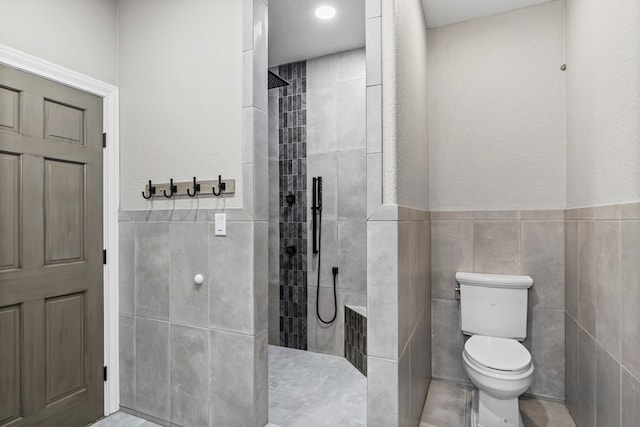 bathroom with toilet, tile walls, and a tile shower