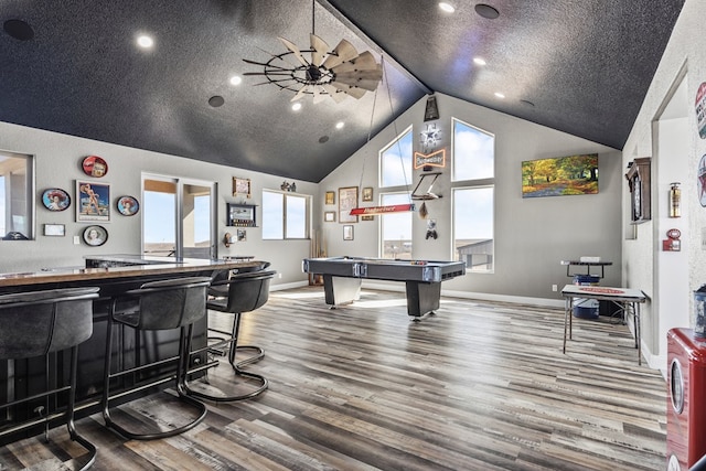 playroom featuring hardwood / wood-style floors, high vaulted ceiling, bar, pool table, and a textured ceiling