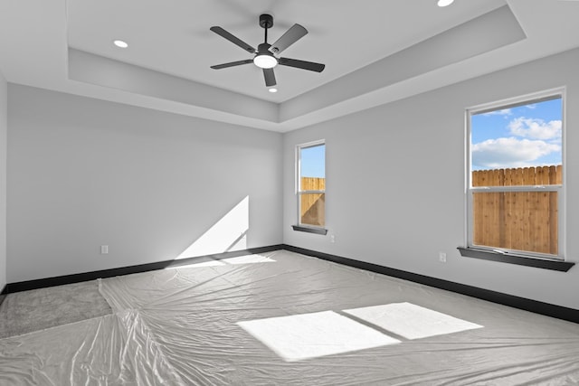 spare room with a raised ceiling, ceiling fan, and a healthy amount of sunlight