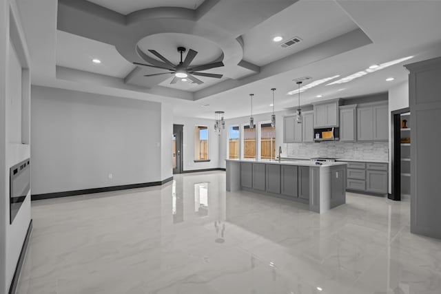 kitchen featuring gray cabinets, a center island, and a tray ceiling