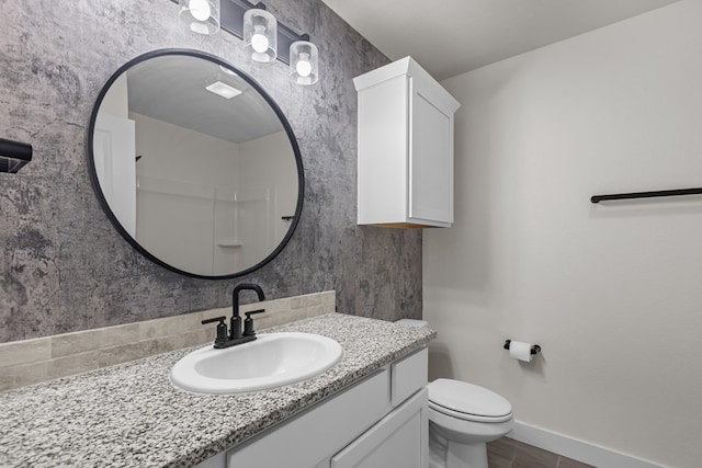 bathroom with vanity, toilet, and baseboards