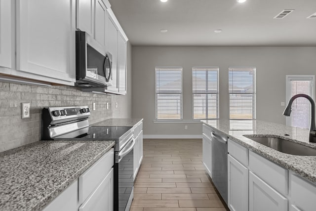 kitchen featuring stainless steel appliances, a sink, visible vents, white cabinetry, and tasteful backsplash