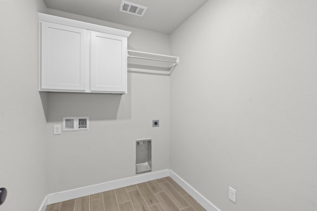 laundry area featuring hookup for a washing machine, visible vents, cabinet space, wood tiled floor, and electric dryer hookup