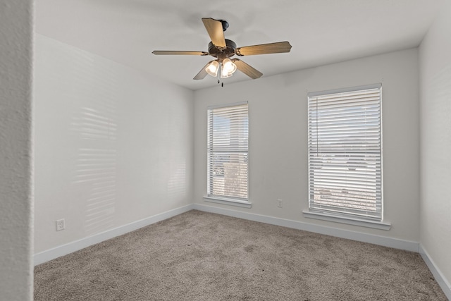 carpeted empty room with a ceiling fan and baseboards