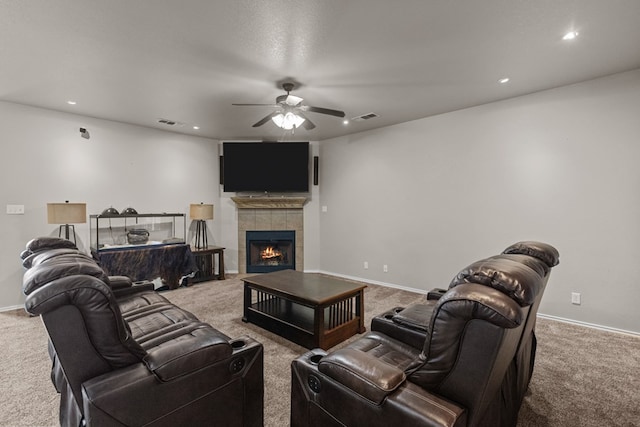 living area featuring a tile fireplace, carpet flooring, visible vents, and a ceiling fan