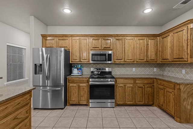 kitchen with appliances with stainless steel finishes, brown cabinetry, visible vents, and decorative backsplash