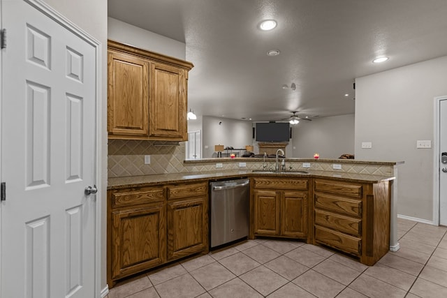 kitchen with tasteful backsplash, brown cabinetry, a sink, dishwasher, and a peninsula