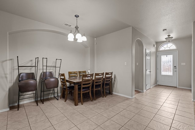 dining area with a chandelier, arched walkways, visible vents, and light tile patterned floors