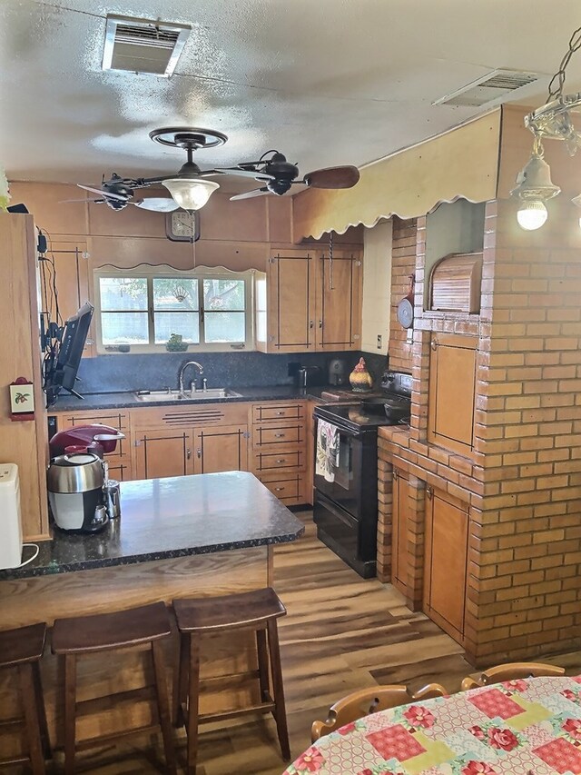 kitchen with a kitchen bar, sink, brick wall, and black electric range