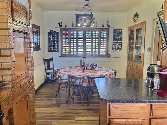 dining room with a chandelier, dark wood-type flooring, wood walls, and ornamental molding