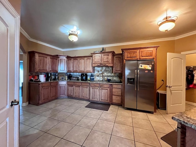 kitchen with light tile patterned floors, stainless steel fridge, decorative backsplash, crown molding, and a sink