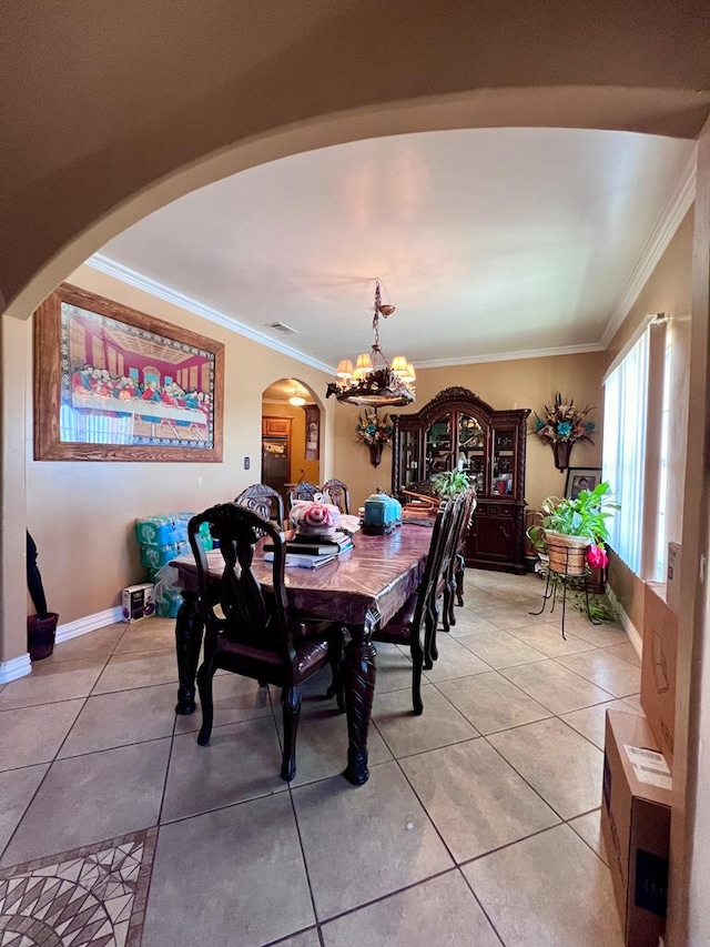 tiled dining room with an inviting chandelier, baseboards, arched walkways, and crown molding