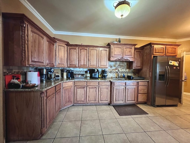 kitchen featuring light tile patterned floors, dark stone countertops, stainless steel fridge, and crown molding