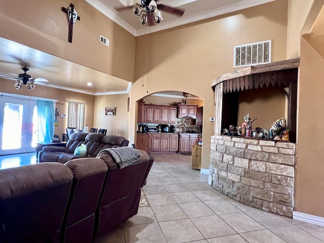 living room featuring arched walkways, visible vents, ornamental molding, light tile patterned flooring, and ceiling fan