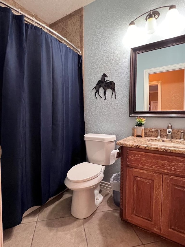 bathroom with toilet, a textured wall, vanity, and tile patterned floors