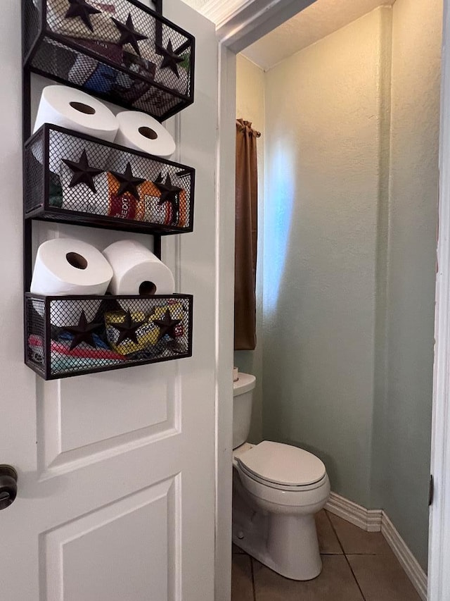 bathroom featuring tile patterned flooring, baseboards, and toilet