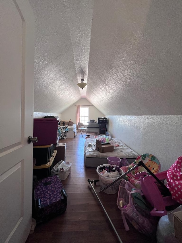 bonus room with a textured ceiling, vaulted ceiling, wood finished floors, and a textured wall