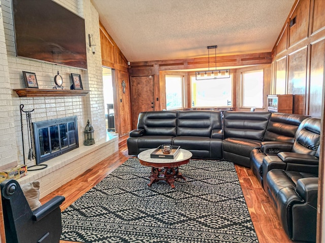 living room with vaulted ceiling, dark hardwood / wood-style floors, wooden walls, a fireplace, and a textured ceiling