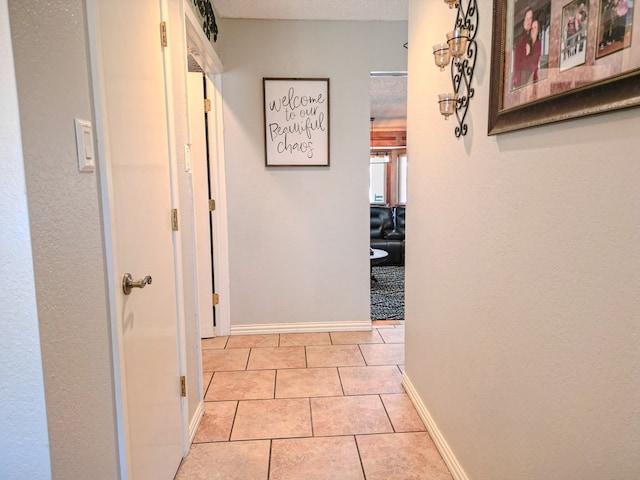 hall featuring a textured ceiling and light tile patterned floors