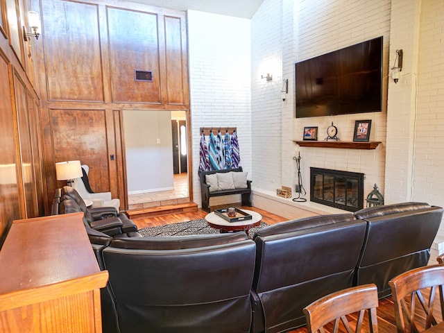 living room with brick wall, hardwood / wood-style floors, and a brick fireplace