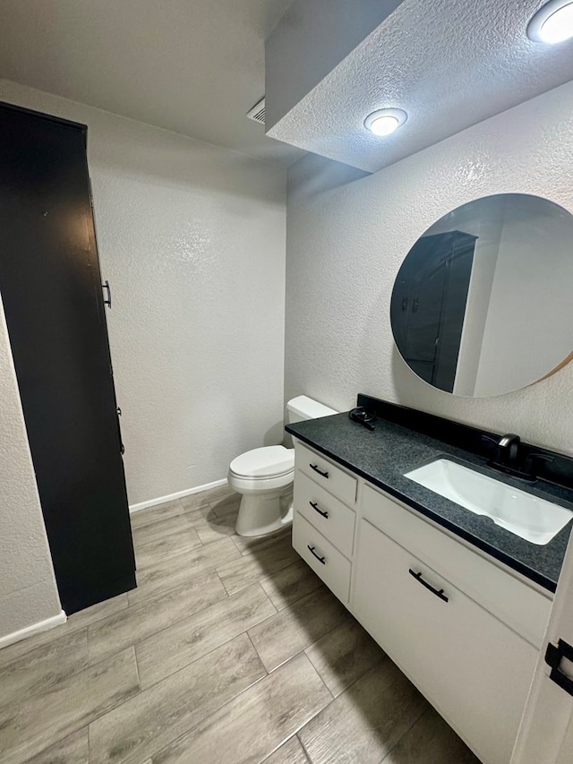 bathroom with vanity, a textured ceiling, and toilet