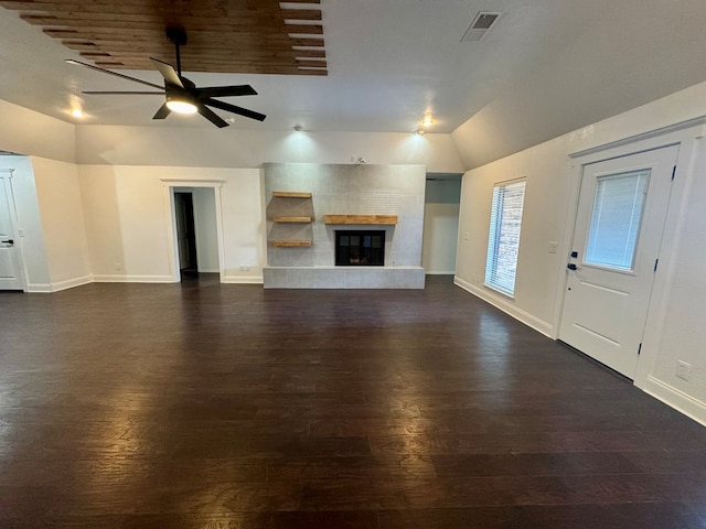 unfurnished living room with a tiled fireplace, vaulted ceiling, dark wood-type flooring, and ceiling fan