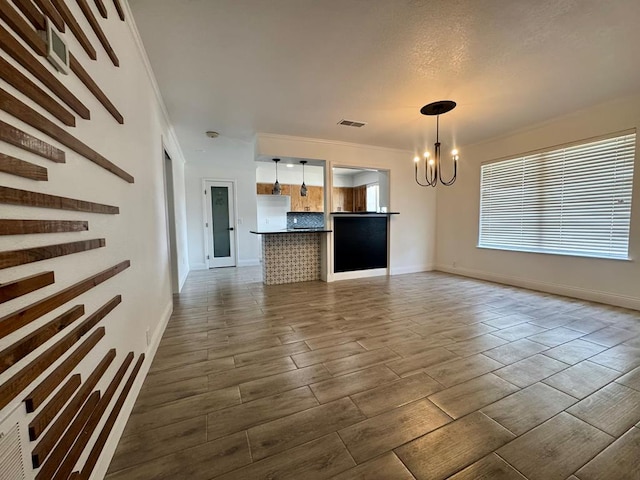 unfurnished living room featuring an inviting chandelier, dark hardwood / wood-style flooring, and crown molding