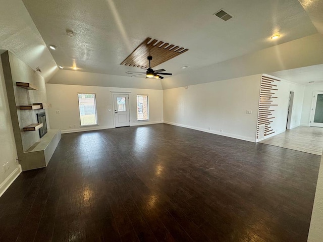 unfurnished living room featuring vaulted ceiling, a textured ceiling, dark hardwood / wood-style floors, ceiling fan, and a fireplace