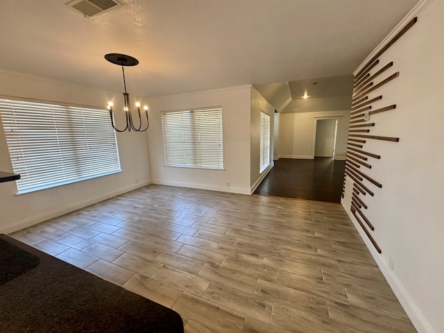 unfurnished dining area featuring ornamental molding, hardwood / wood-style floors, and a chandelier