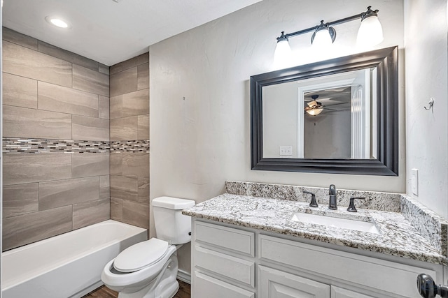 full bathroom featuring vanity, ceiling fan, toilet, and tiled shower / bath