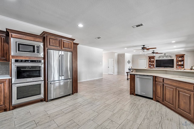 kitchen with appliances with stainless steel finishes, a textured ceiling, ceiling fan, and sink