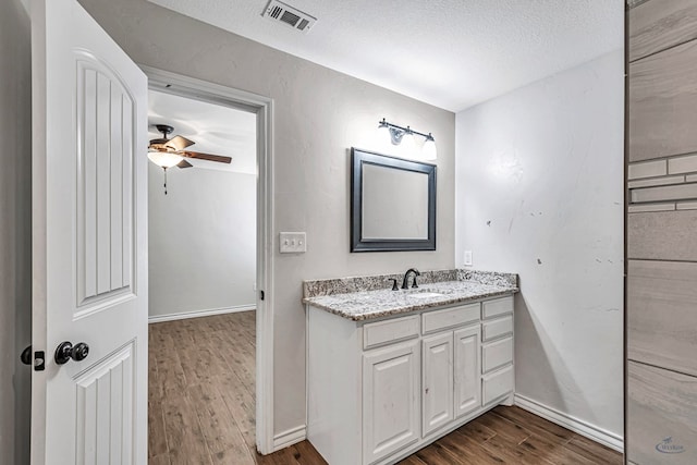 bathroom with hardwood / wood-style flooring, vanity, ceiling fan, and a textured ceiling