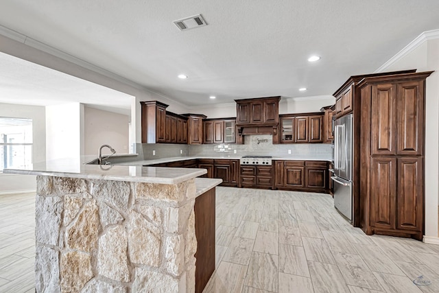 kitchen featuring dark brown cabinets, crown molding, kitchen peninsula, and stainless steel appliances