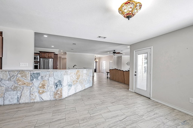 kitchen featuring ceiling fan, sink, stainless steel appliances, kitchen peninsula, and a textured ceiling