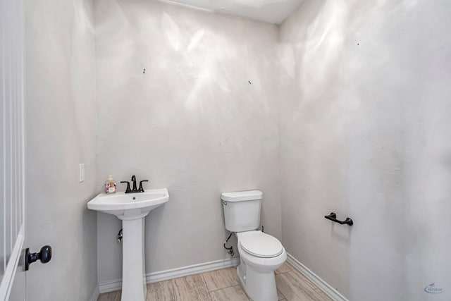 bathroom with hardwood / wood-style floors, toilet, and sink