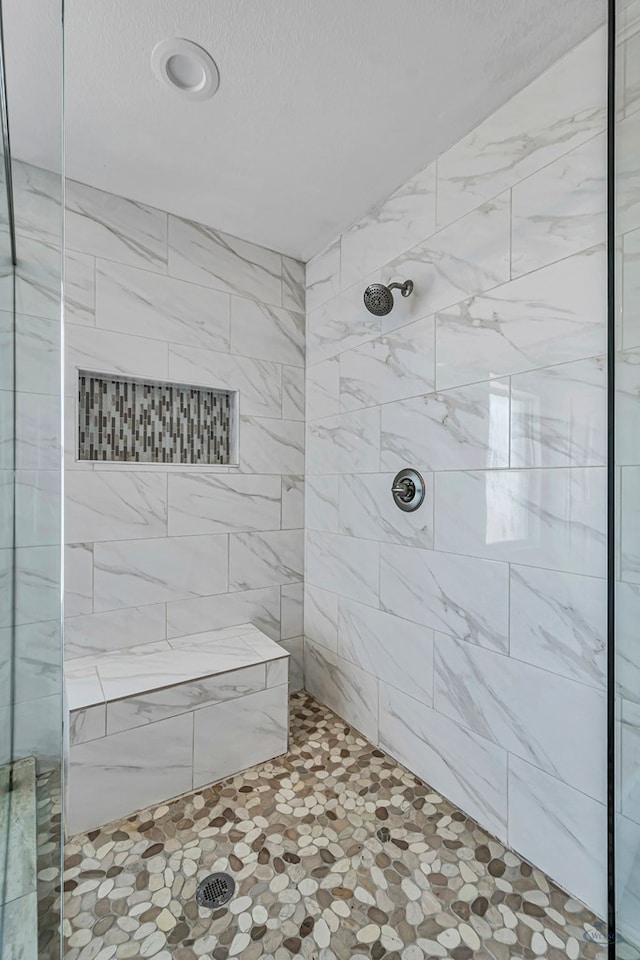 bathroom featuring a tile shower and a textured ceiling