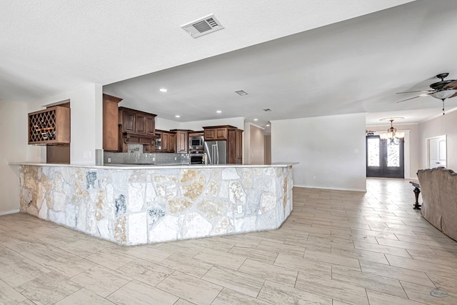 kitchen featuring kitchen peninsula, appliances with stainless steel finishes, decorative backsplash, french doors, and ceiling fan