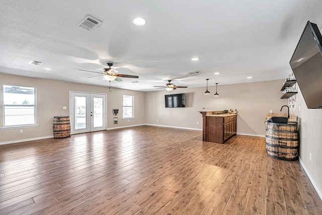 unfurnished living room featuring hardwood / wood-style flooring, ceiling fan, and french doors