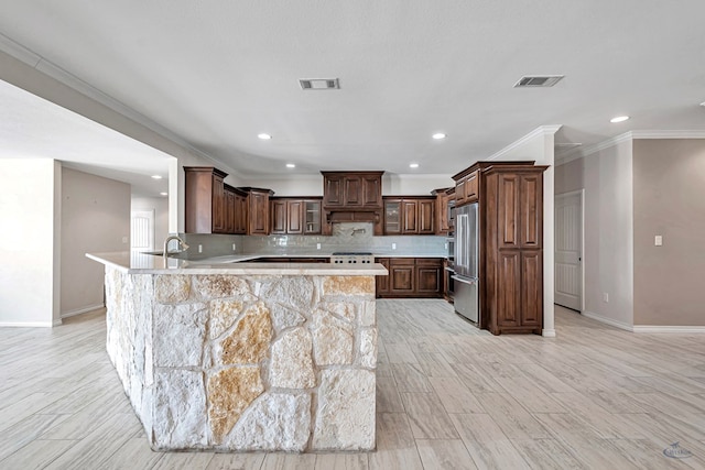 kitchen featuring backsplash, kitchen peninsula, high quality fridge, dark brown cabinets, and light wood-type flooring