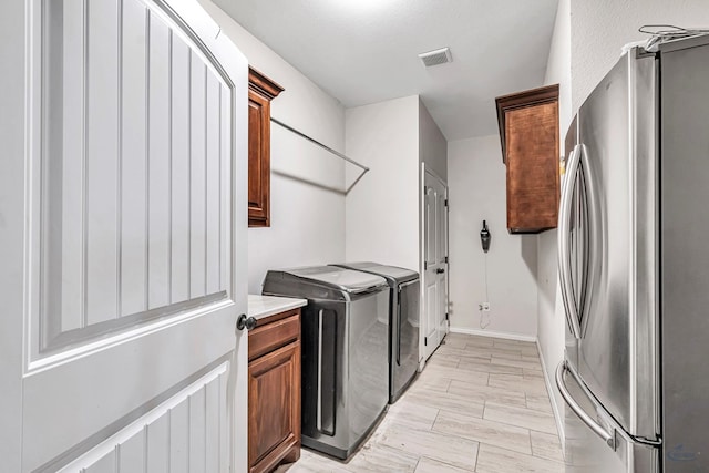 laundry area featuring a textured ceiling, cabinets, light wood-type flooring, and independent washer and dryer