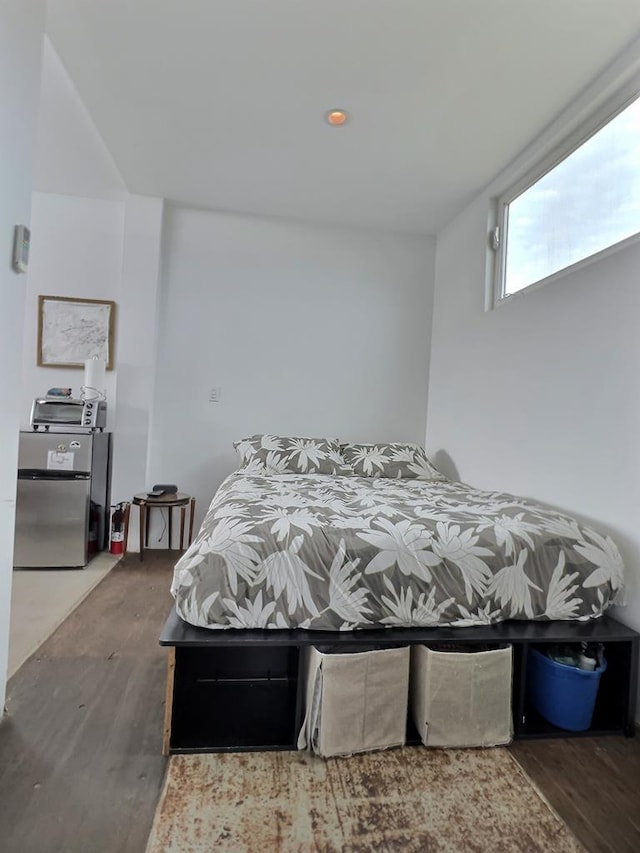 bedroom featuring dark wood-type flooring and stainless steel refrigerator