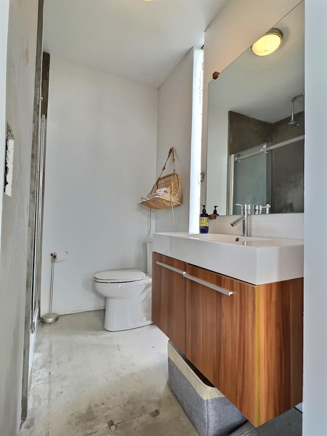 bathroom with concrete flooring, vanity, toilet, and a shower with shower door