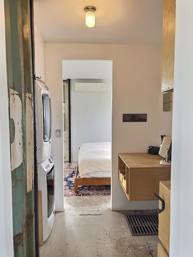 bathroom with a wall mounted air conditioner, stacked washer and dryer, and concrete floors