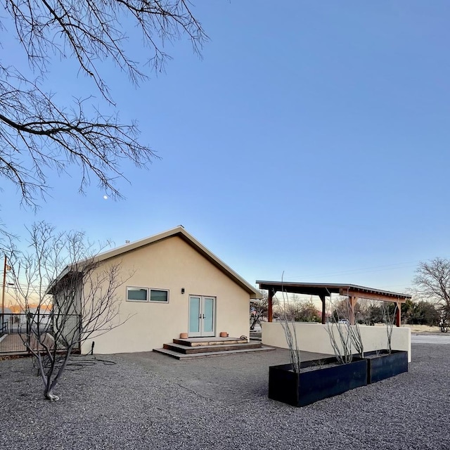 back of property featuring french doors, fence, and stucco siding